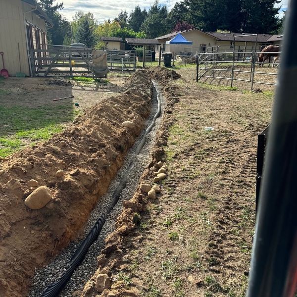 Trench dug for French drain installation with perforated pipe and gravel by Nate’s Junk Removal in Washington State