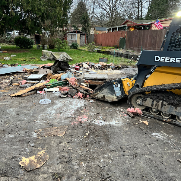 Skid steer clearing demolition debris from residential lot in Washington State