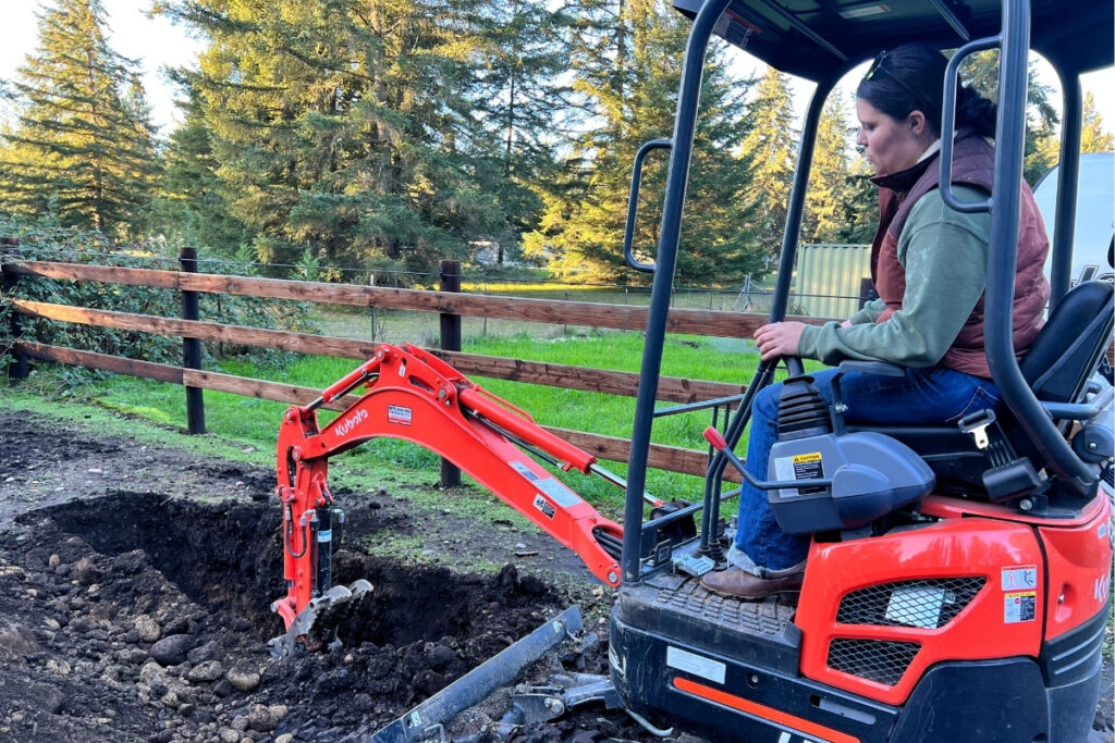 Team member operating a Kubota mini excavator to dig on a residential property in Washington State